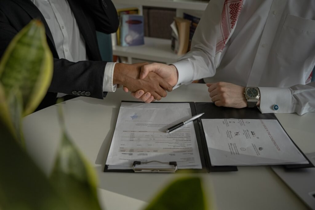 Agent and vendor shaking hands over a signed agency agreement