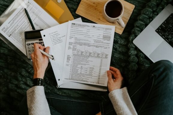 Person checking loan documents with a calculator and laptop