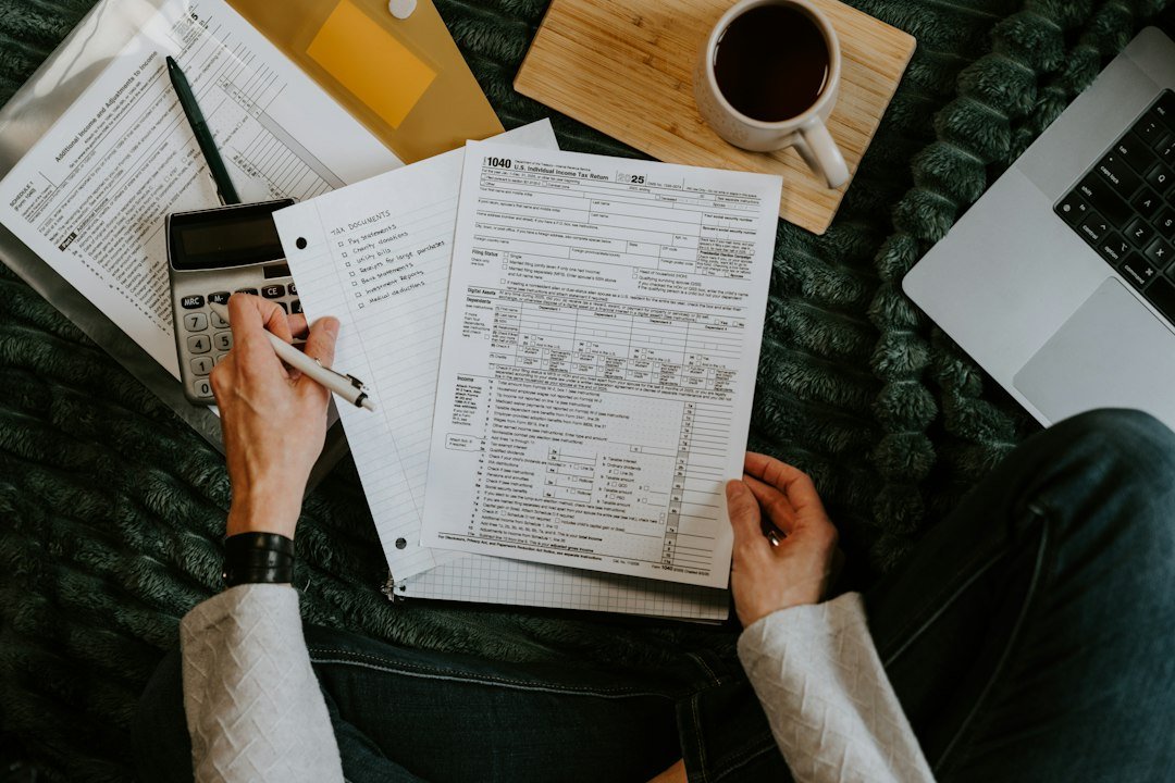 Person checking loan documents with a calculator and laptop